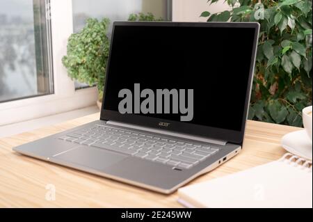 Moscow, Russia - January 22, 2020: Laptop ACER Swift. Laptop with blank black screen, notebook and coffee cup on Home Office Desk. Stock Photo