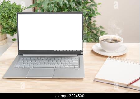 mockup laptop on wooden table, Front view of the laptop is on work table with notebook and cup of coffee. Laptop or notebook with blank screen on wood Stock Photo