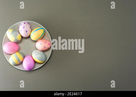 Decorated Easter eggs on a plate on a gray background with place for text. View from above. Trending gray 2021. Stock Photo
