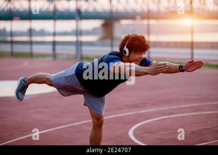 Strong fit young man doing balance exercises outside early in the morning. Stock Photo