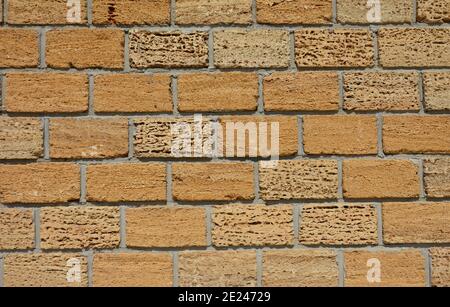 A close-up of an old yellow limestone, shell rock brick wall or fence. Coquina rock, limestone brick wall background. Stock Photo
