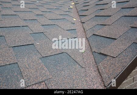 A close-up of asphalt shingled roof corner, roof intersection with roof flashing installed to prevent water leaks. Inspecting of a roof problem area, Stock Photo