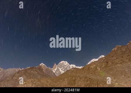 star trails with blue sky in moonlight over the snow mountains of hunza , Karakorum range gilgit Baltistan Stock Photo