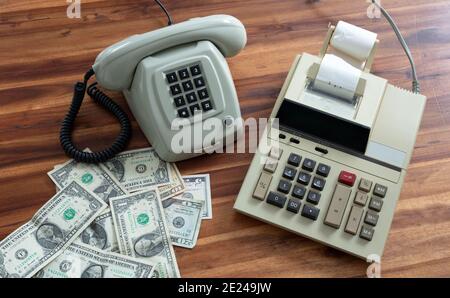 Old fashioned calculator, telephone and dollars on desk Stock Photo