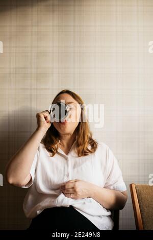 Pregnant woman drinking coffee in kitchen Stock Photo