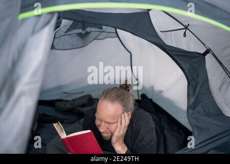 Man reading book in tent Stock Photo