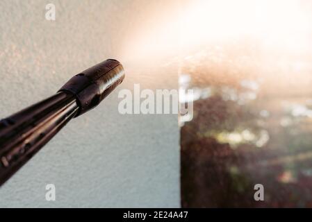 power washing the wall - cleaning the facade of the house - focus on the tip of the spray nozzle- shallow depth of field Stock Photo