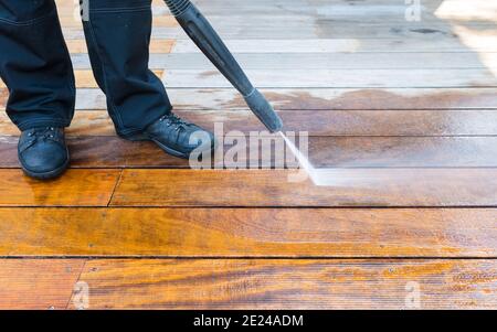 power washing - man cleaning terrace with a power washer - high water pressure cleaner on wooden terrace surface Stock Photo