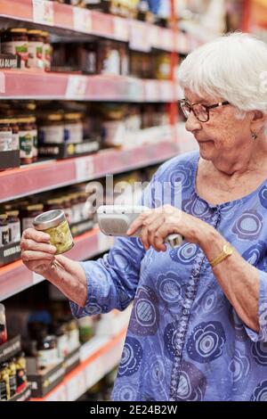 Senior woman using barcode reader in shop Stock Photo