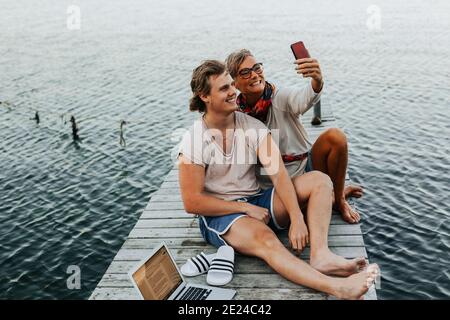 Mother with adult son on jetty taking selfie Stock Photo