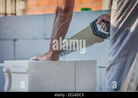 Closeup of a man builder using a saw for house construction from the gas silicate block Stock Photo