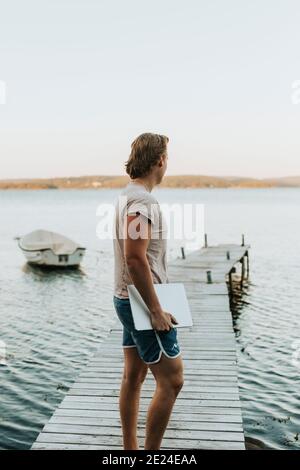 Man on jetty holding laptop Stock Photo