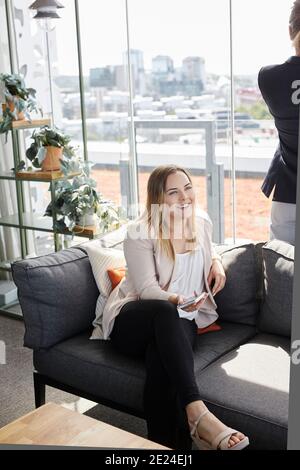 Smiling woman sitting on sofa Stock Photo