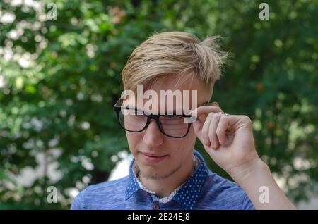 Portrait of stylish young man wearing glasses.  Handsome young man in stylish glasses with fashionable hairstyle in fashionable blue shirt posing on t Stock Photo
