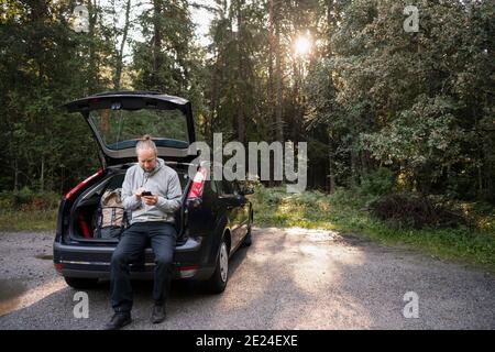 Man near parked car using cell phone Stock Photo