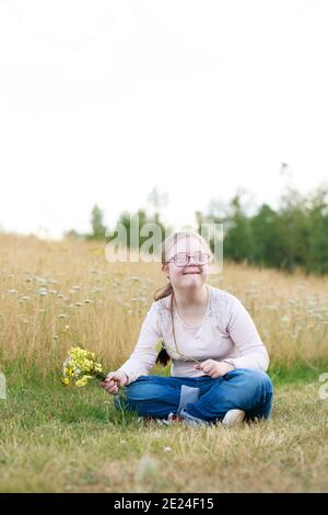 Smiling girl on meadow holding wildflowers Stock Photo