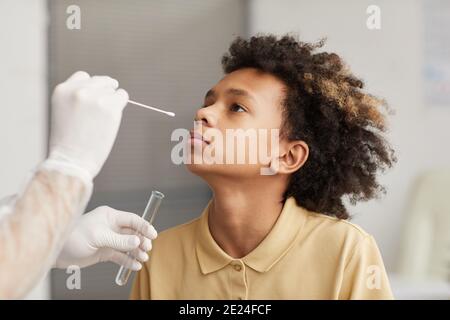 Portrait of African-American boy taking covid swab test during examination in medical clinic, copy space Stock Photo