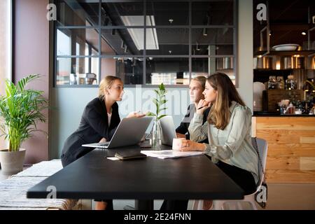 Female coworkers talking in cafe Stock Photo