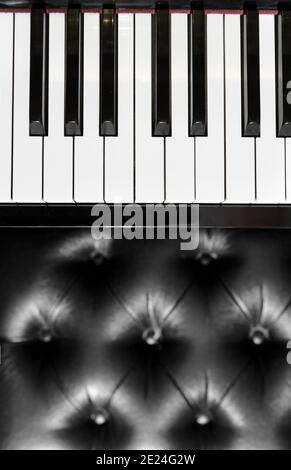 Top down view on piano keyboard and upholstered leather stool in vertical format in a music or entertainment concept Stock Photo