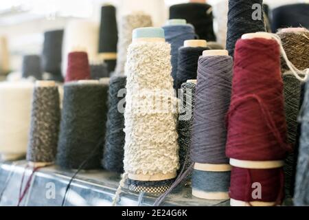 Spools and reels of spun cashmere wool or yarn in assorted colors and textures on a shelf in close up Stock Photo