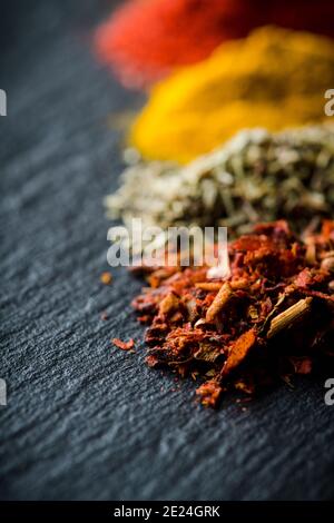 Bright and colorful spices on the black stone background. Different spices and herbs for background. Stock Photo