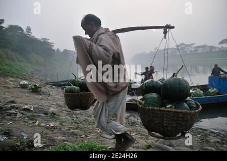 Farmers from rural areas bring their vegetables on boat to the nearest market on a foggy winter morning. Sylhet, Bangladesh. Stock Photo