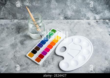 Artistic brush palette jar with water and watercolor paints Stock Photo