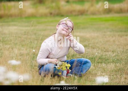 Smiling girl on meadow holding wildflowers Stock Photo