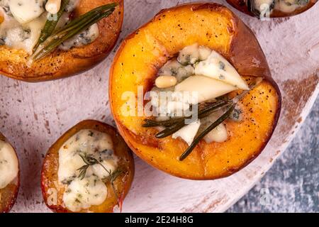 Grilled baked peach and plums stuffed with blue cheese dorblu and rosemary. Top view. Close up Stock Photo