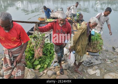 Farmers from rural areas bring their vegetables on boat to the nearest market on a foggy winter morning. Sylhet, Bangladesh. Stock Photo