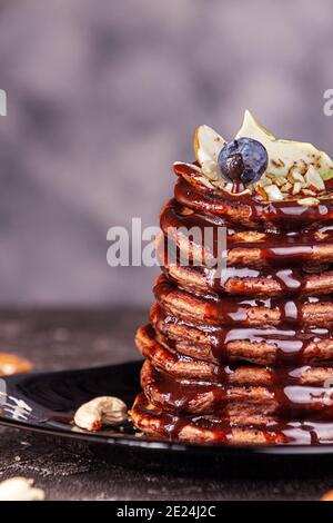 Vegan pancakes based avocado with cocoa and date syrup. Vegan healthy sweet food. Dark background Stock Photo