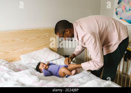 Father changing babys diaper on bed Stock Photo
