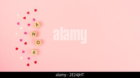 Word AMOR on wooden cubes and hearts on a pink background. Copy space. sob Stock Photo