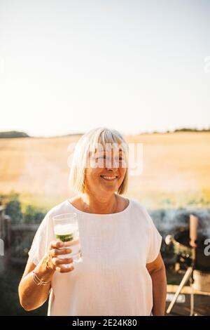 Smiling woman in garden holding drink Stock Photo