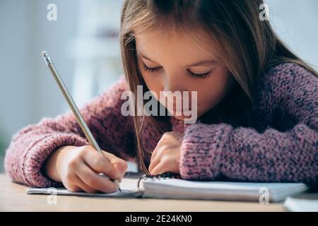 Girl with pencil writing in notebook on blurred background Stock Photo