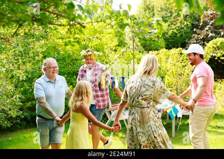Family dancing in garden around maypole Stock Photo