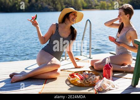 Happy female friends having picnic on jetty Stock Photo