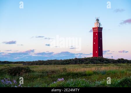 Lighthouse standing on the Dutch coast with a dramatic. and colorful dusk or dawn sky behind it. High quality photo Stock Photo