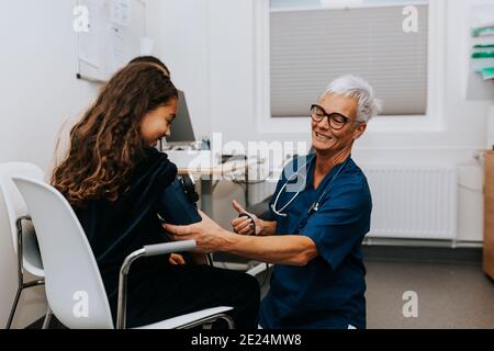 Doctor checking girls blood pressure Stock Photo