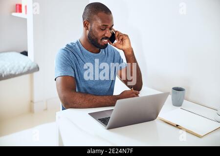 Worker noting down information from a phone chat Stock Photo