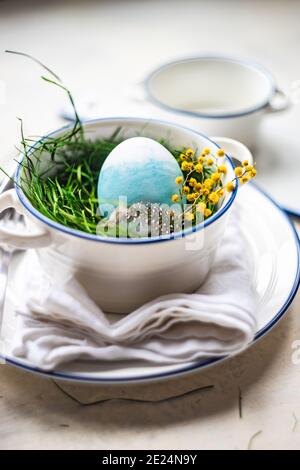 Easter place setting with an Easter egg, flowers and a feather Stock Photo