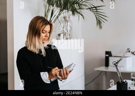 Woman taking notes in office Stock Photo