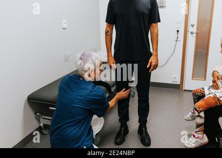 Doctor examining mans knee in office Stock Photo
