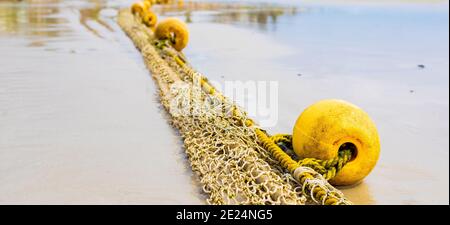Buoys on a rope stretching from wet sandy coast to the ocean in Cape Town, South Africa Stock Photo