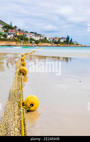 Buoys on a rope stretching from wet sandy coast to the ocean in Cape Town, South Africa Stock Photo