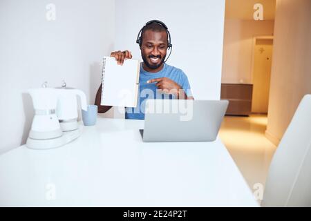 Multiracial employee taking up a notepad and showing a page Stock Photo