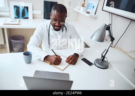 Cheerful doctor touching a sheet of paper with pencil Stock Photo