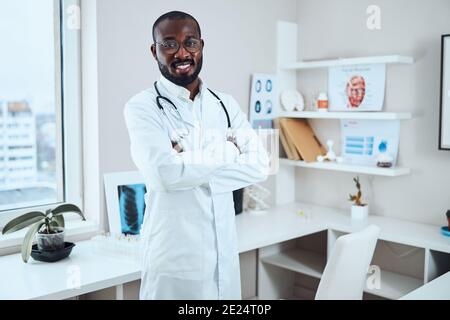 Happy doctor staying with crossed arms in an office Stock Photo
