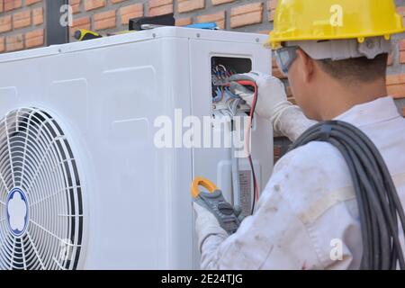 Engineer installing an air conditioning unit, Thailand Stock Photo