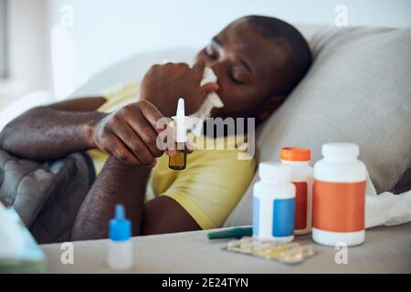 Multiethnic sick person bringing the drops to his face Stock Photo
